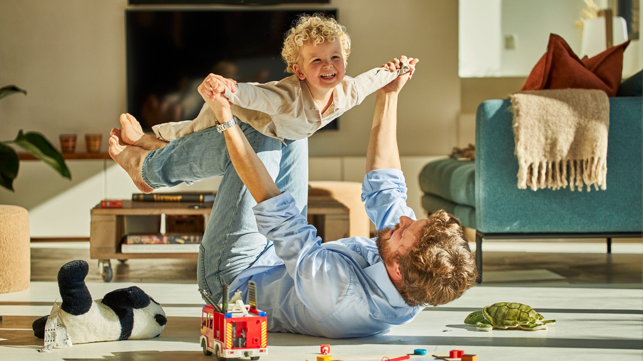 Oče in njegov otrok se veselo igrata skupaj ter uživata v toplini talnega ogrevanja