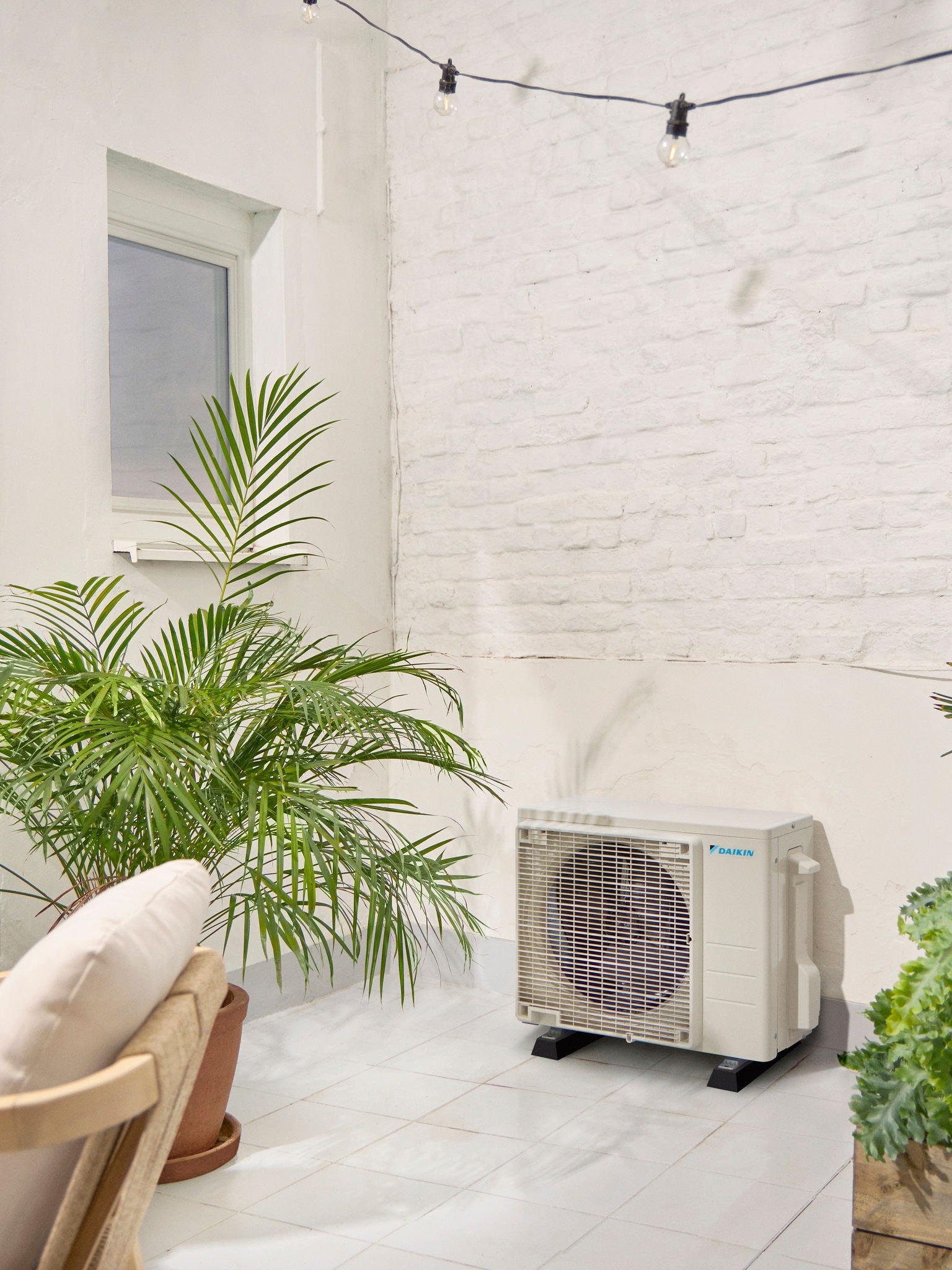 Zunanja enota Daikin na beli terasi z rastlino