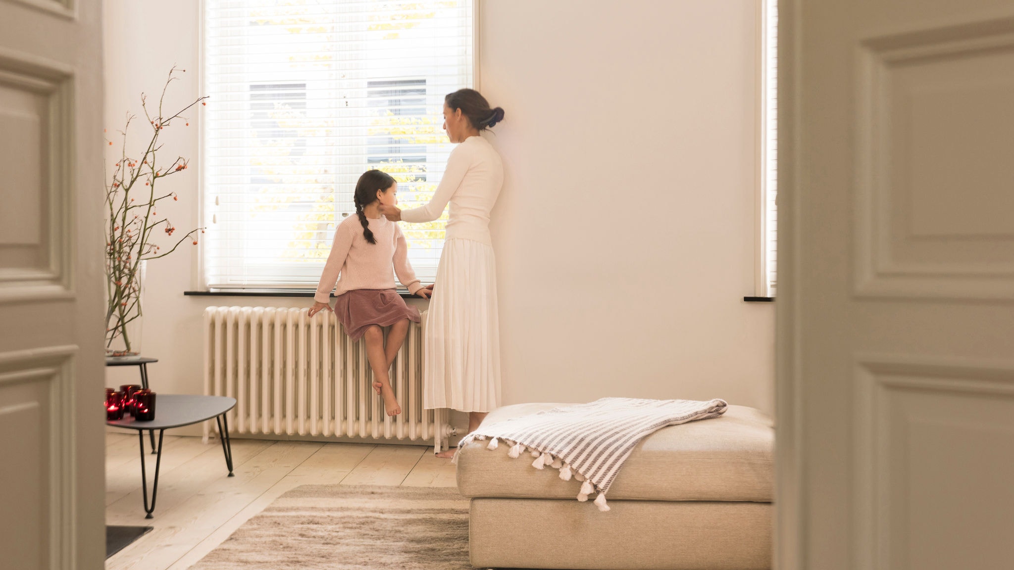 Mama in hčerka gledata skozi okno v svoji odlično ogrevani dnevni sobi