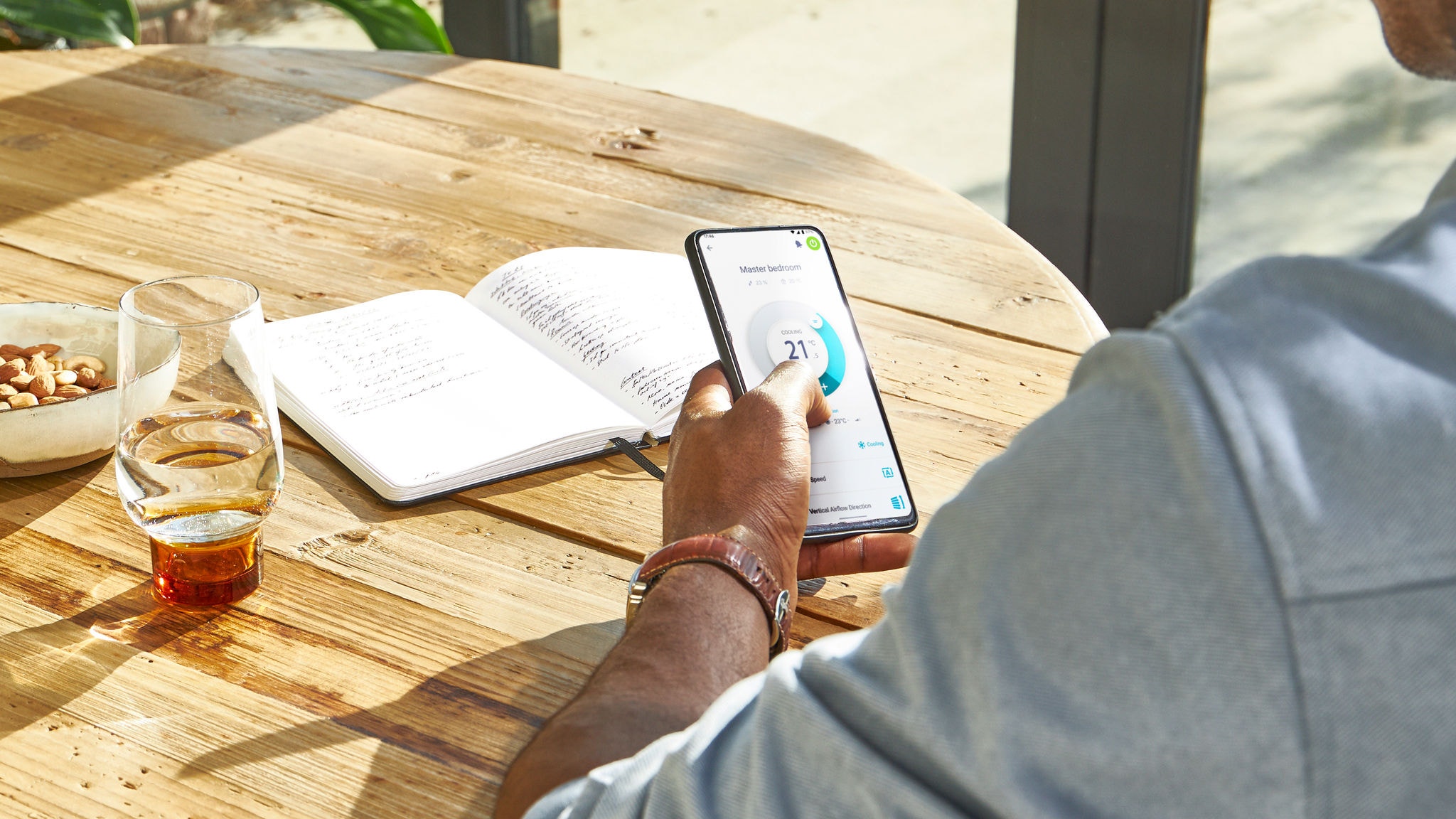 Moški upravlja temperaturo svoje hiše z aplikacijo Daikin Onecta na pametnem telefonu od koder koli