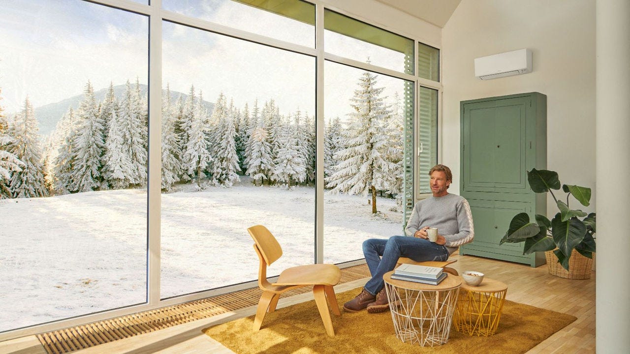 Moški sedi na kavču in uživa v ogrevanju s klimatsko napravo