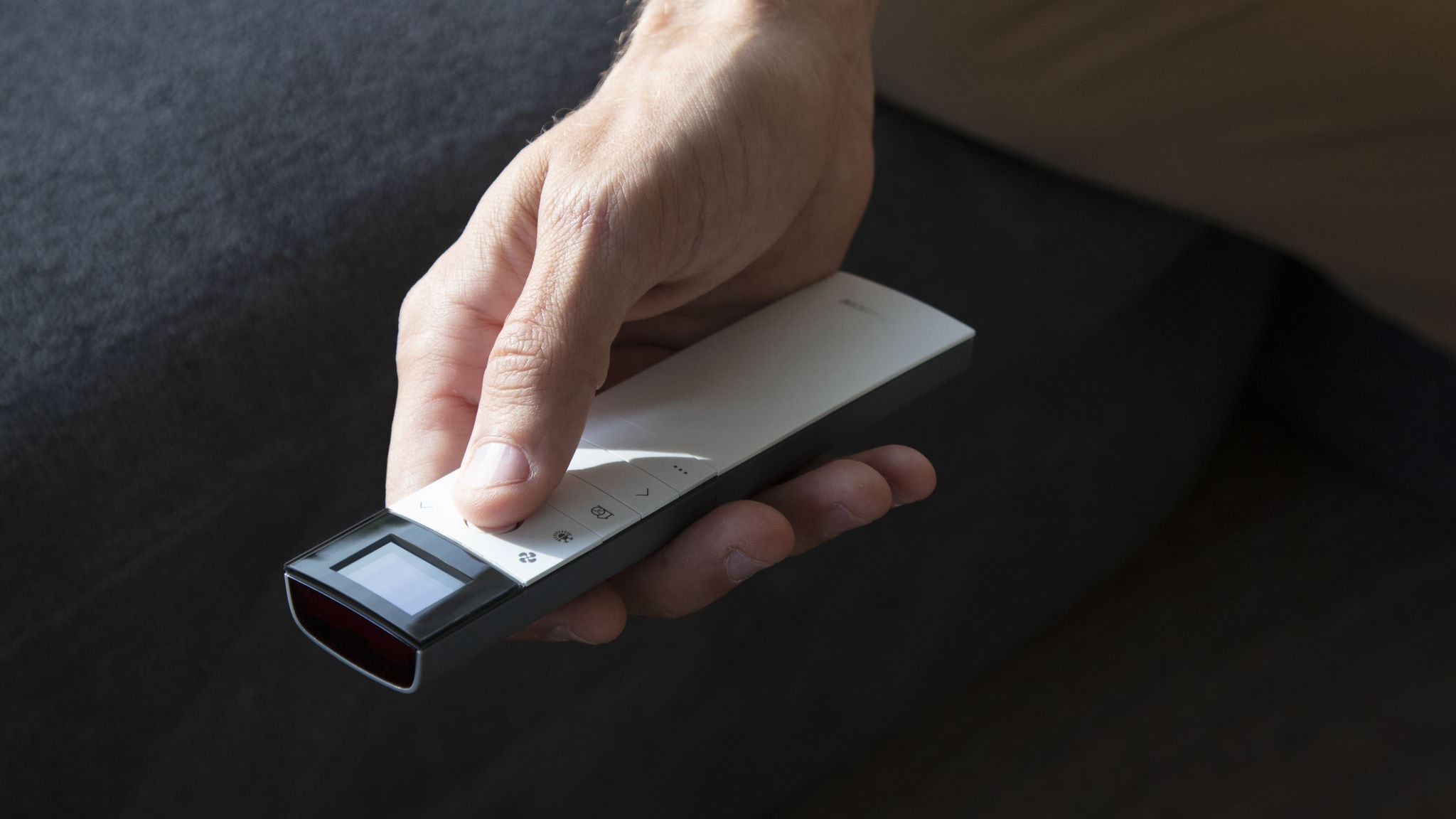 Moški z daljinskim upravljalnikom upravlja svojo klimatsko napravo v dnevni sobi