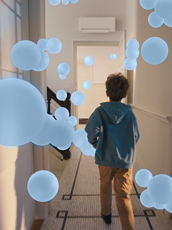 Deček se sprehaja po hodniku z enakomernim in uravnoteženim pretokom zraka, ki ga omogoča dobro zasnovan sistem s toplotno črpalko zrak–zrak