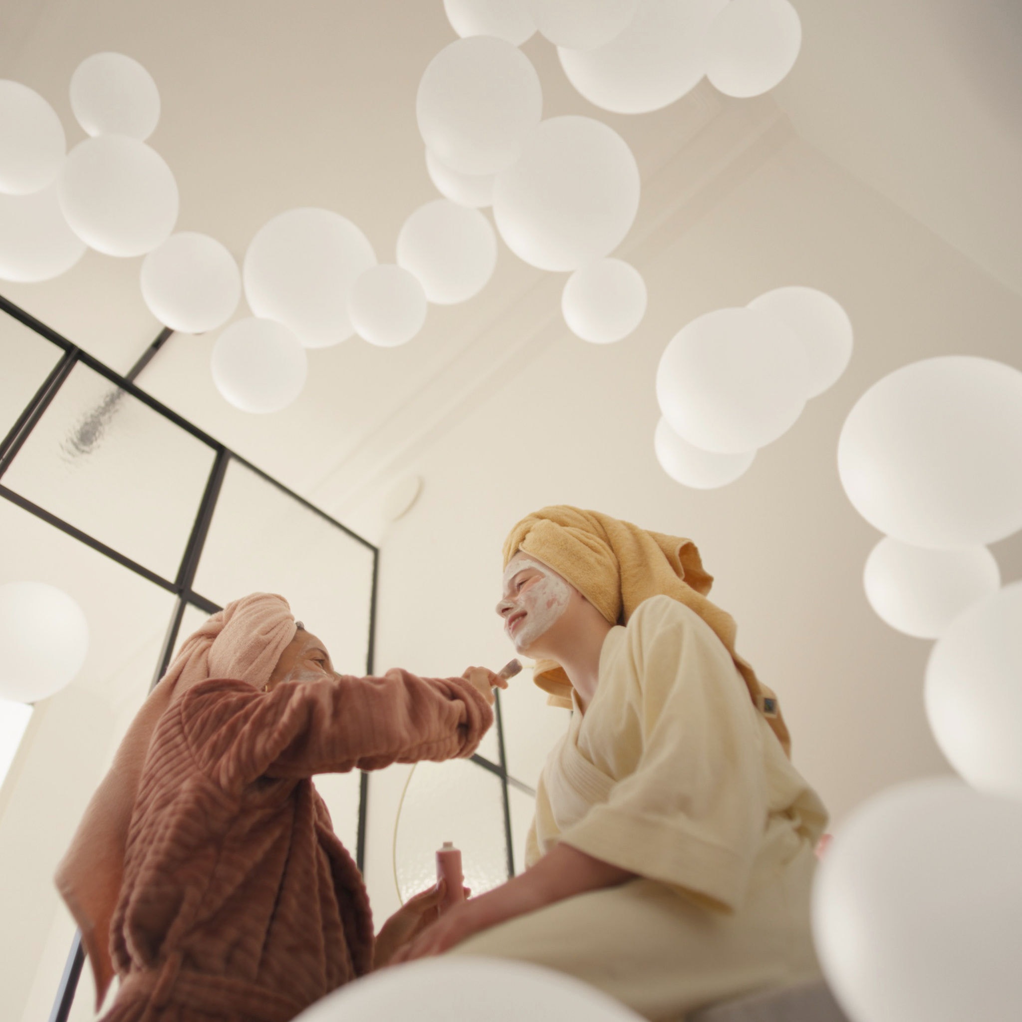 Mati in hči uživata v razvajanju z obraznimi maskami v dobro prezračeni sobi po zaslugi sistema za prezračevanje s svežim zrakom