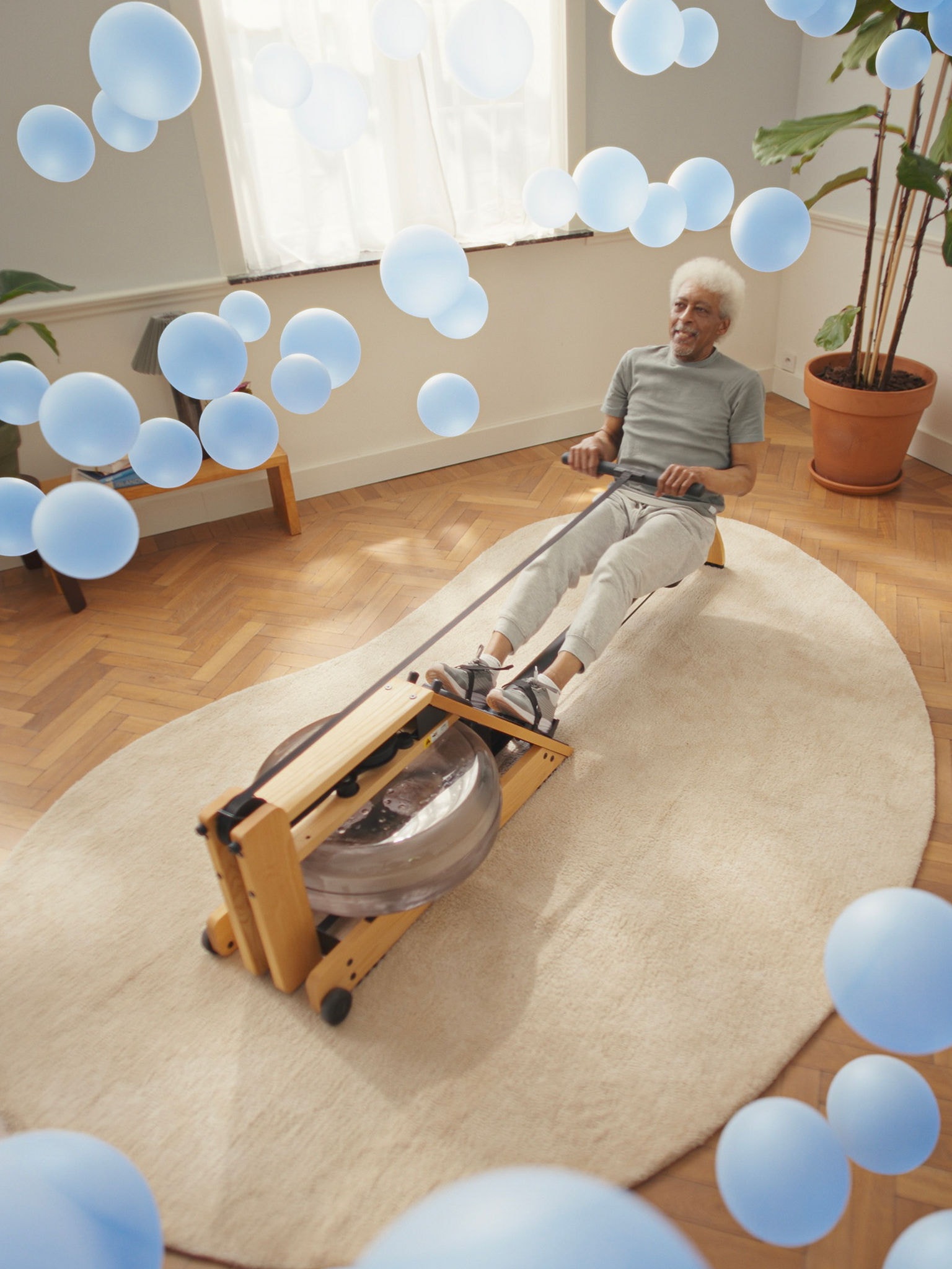 Starejši moški vadi na veslaški napravi v prostoru s popolno klimatizacijo po zaslugi odzivne tehnologije toplotne črpalke zrak–zrak