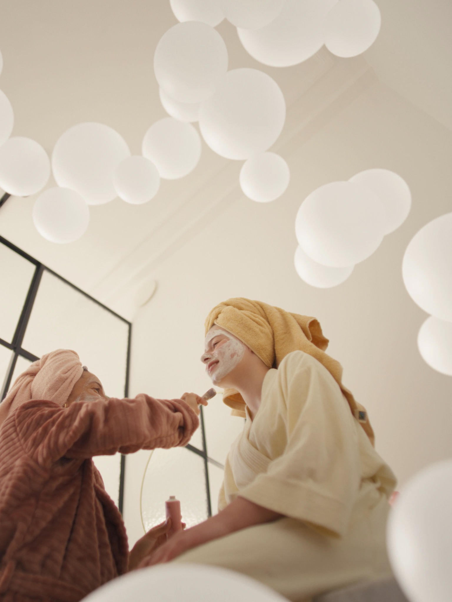 Mati in hči uživata v razvajanju z obraznimi maskami v dobro prezračeni sobi po zaslugi sistema za prezračevanje s svežim zrakom