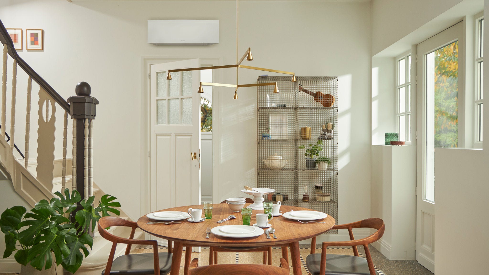 Soba z velikim oknom, leseno mizo in črno stensko klimatsko napravo