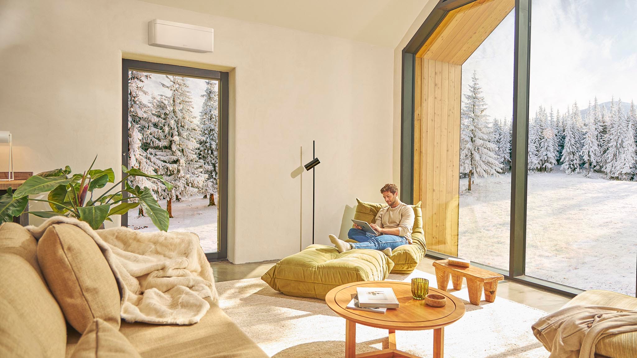 Moški sedi na kavču in uživa v ogrevanju s klimatsko napravo